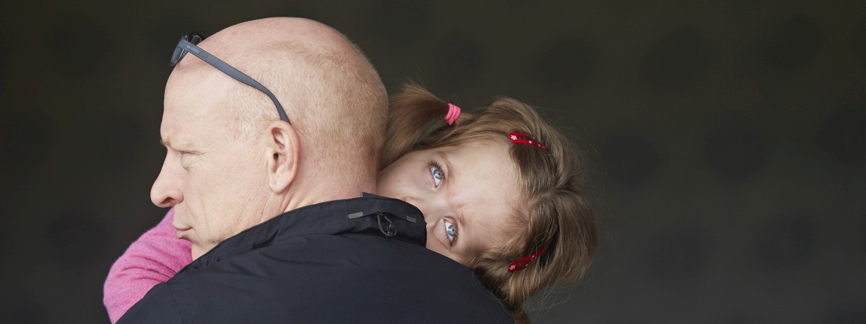 Ein Mädchen ruht sich auf der Schulter ihres Vaters aus.