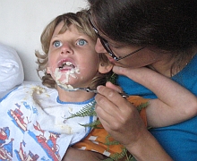 Ein Mädchen mit Behinderung wird mit Brei gefüttert.