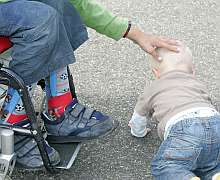 Ein Junge im Rollstuhl streicht seinem Babybruder über den Kopf